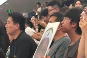 詹姆斯中国行成都活动现场 一球迷拿着詹姆斯经典哭脸照坐在场边 詹姆斯中国行成都活动现场 一球迷拿着詹姆斯经典哭脸照坐在场边